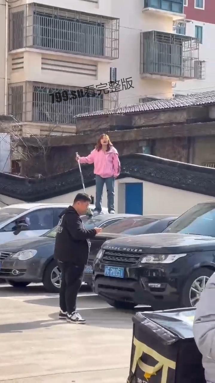 江苏南通 有一女子站在车上 还砸坏车辆 疑似精神有问题